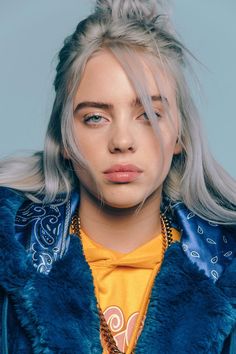 a woman with blonde hair wearing a blue jacket and yellow t - shirt is looking at the camera