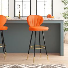 two orange chairs sitting on top of a wooden floor next to a kitchen countertop