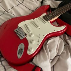 a red electric guitar laying on top of a bed