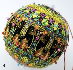 an artistically decorated ball on a stand with beaded trimmings and beads