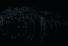 the dark cave is filled with icicles and water