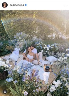 a man and woman are sitting on the ground surrounded by flowers