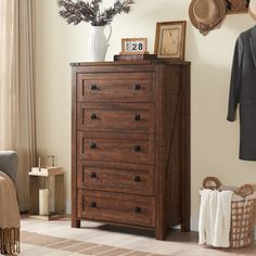 a brown chest of drawers sitting in a living room next to a chair and coat rack