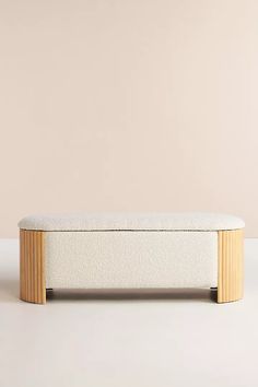 a white bench sitting on top of a floor next to a beige wall and wooden frame