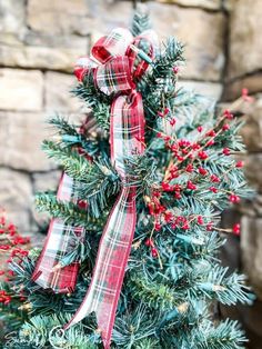 a christmas tree decorated with red and white plaid ribbon, bows and mistlet berries