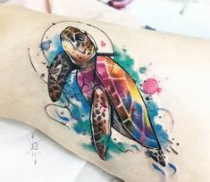 a watercolor tattoo with a turtle on it's arm and colorful ink splots