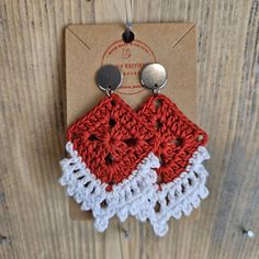 two red and white crocheted earrings hanging from a brown carded hanger