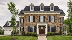 a large brick house with black shutters on the front and side windows, surrounded by lush green grass