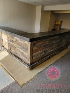 a large wooden counter sitting in the middle of a room next to a wall with a donut sign on it