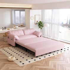 a pink couch sitting on top of a hard wood floor next to a large window