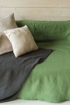 pillows and blankets on a bed with green sheets