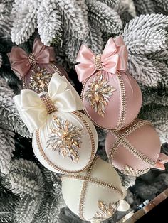 three christmas ornaments with bows on them sitting next to pine cones and fir tree branches