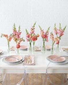 the table is set with pink flowers and plates