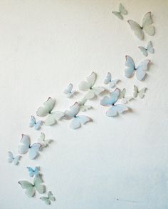 a group of butterflies flying in the air on a white wall with no one around them