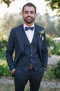 a man in a tuxedo poses for the camera with his hands in his pockets