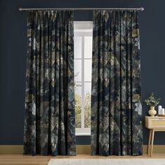 a living room with blue walls and floral curtains on the windowsill, along with a white rug