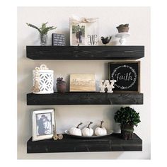 two black shelves with white pumpkins and other items on top of each shelf in front of the wall