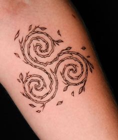 a woman's arm with three spiral tattoos on it