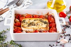 a white dish filled with tomatoes and fish