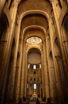 the interior of an old church with stone columns and arches on either side, looking up at the altar