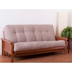 a wooden futon couch sitting on top of a hard wood floor next to a potted plant