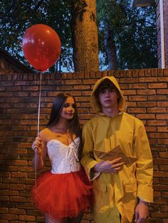 a man and woman dressed in costumes standing next to each other with a red balloon