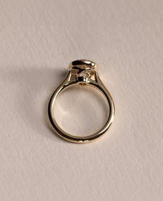 a gold ring with a single diamond on the top, sitting on a white surface