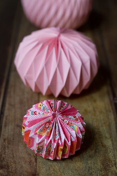 two pink paper balls sitting on top of a wooden table