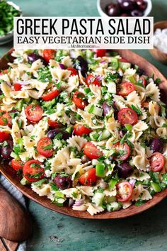 greek pasta salad in a wooden bowl on a green table