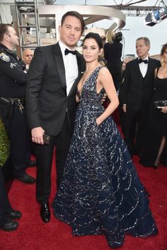 two people standing next to each other on a red carpet