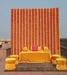 an orange and yellow wedding set up with flowers on the wall behind it, in front of a backdrop