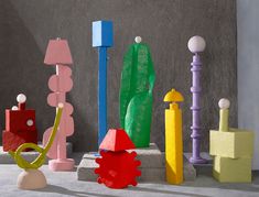 an assortment of brightly colored objects are on the ground next to each other in front of a gray wall