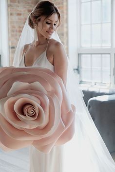 a woman in a wedding dress holding a giant rose