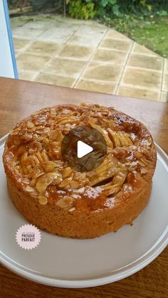 a cake sitting on top of a white plate next to a wooden table with a window