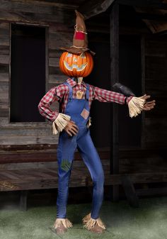 a scarecrow wearing overalls and a pumpkin hat