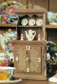 a wicker grandfather clock on display in front of other china dishes and vases