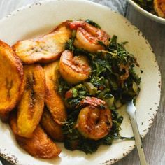 a white plate topped with shrimp and greens next to a bowl filled with other food