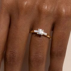 a woman's hand with a diamond ring on top of her left hand, showing the middle finger