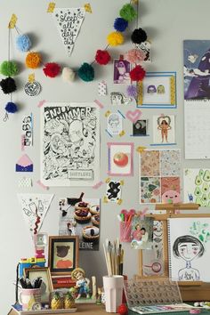 the wall is covered with many different pictures and art pieces, including paper pom poms