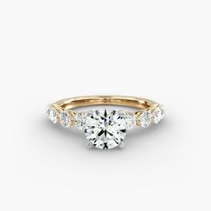 a yellow gold engagement ring with three stones on the band and an oval center stone