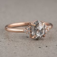 a close up of a diamond ring on a concrete surface with the center stone surrounded by smaller diamonds