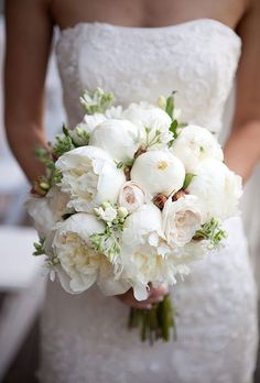 a bride holding a bouquet of white flowers