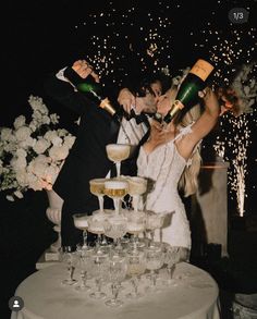 a newly married couple standing next to each other in front of champagne flutes