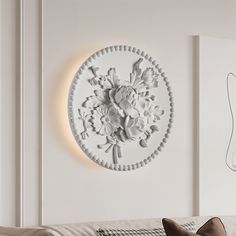 a living room with a white couch and wall decoration on the wall above it is a circular light fixture