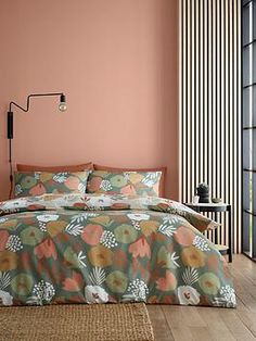 a bed in a room with pink walls and wooden flooring next to a window