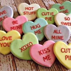 heart shaped cookies with words on them sitting on top of a wooden table next to each other