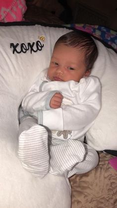 a baby laying on top of a white pillow