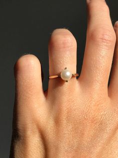 a woman's hand with a pearl ring on it