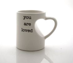 a white coffee mug with the words you are loved written on it and a heart - shaped handle