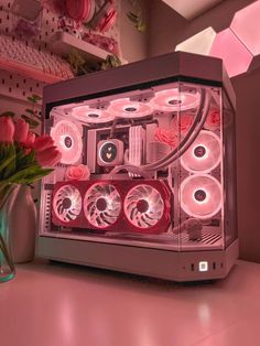 a computer case sitting on top of a table next to a vase filled with flowers